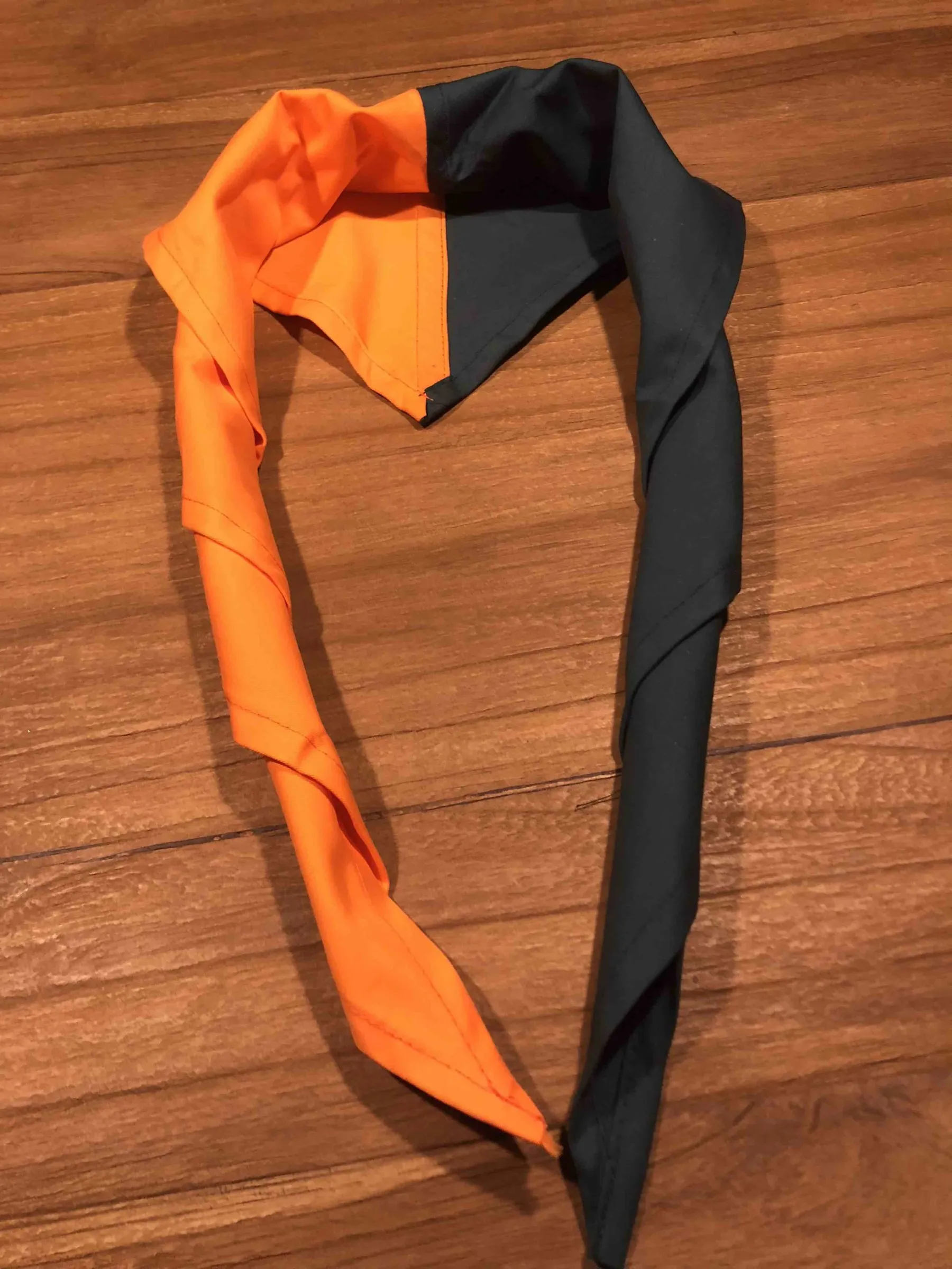 Oranje met zwarte scoutingdas van Scouting Nunspeet op een houten tafel