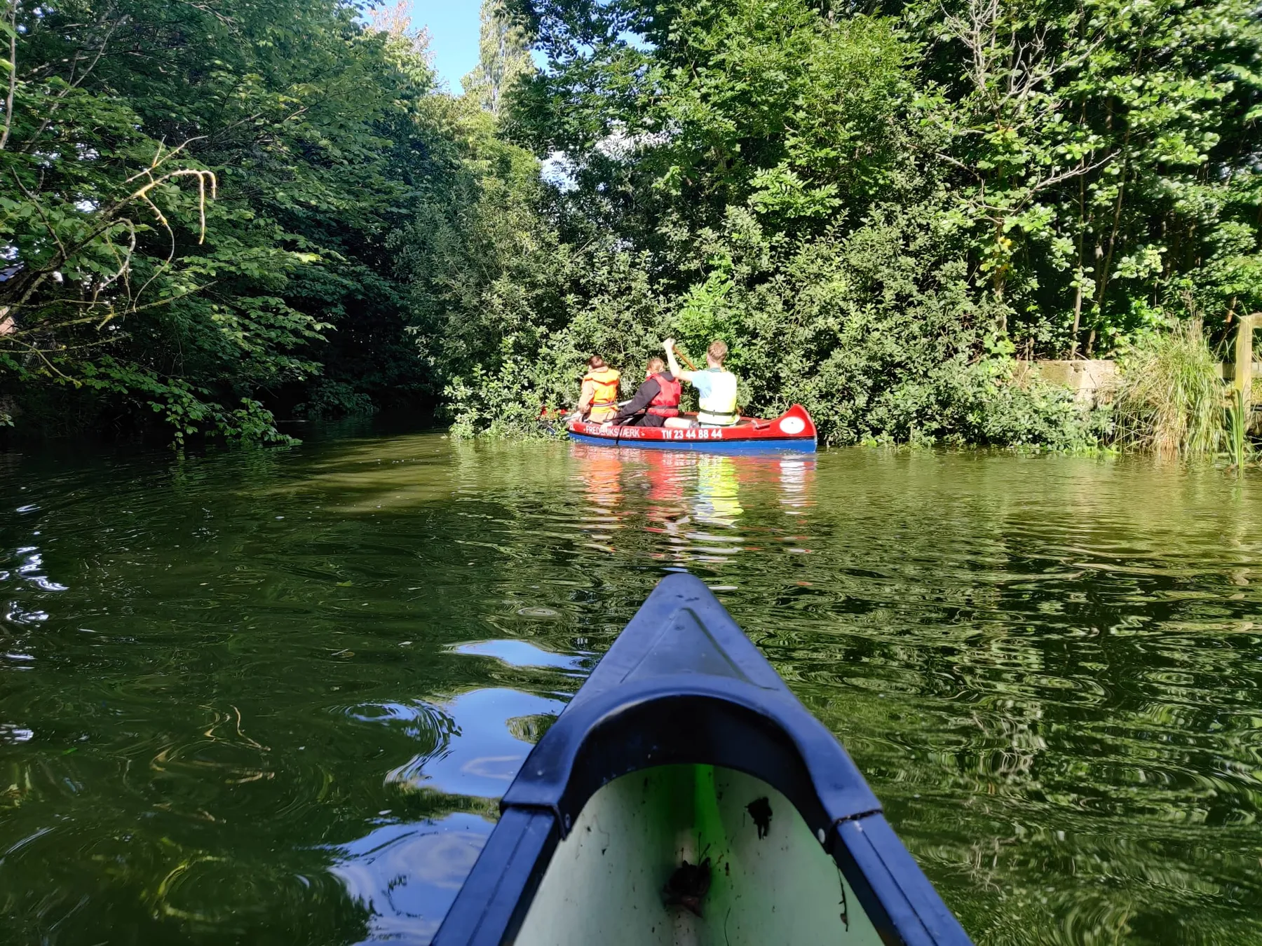 Explorers varen in kano's over een groene rivier tussen de bomen