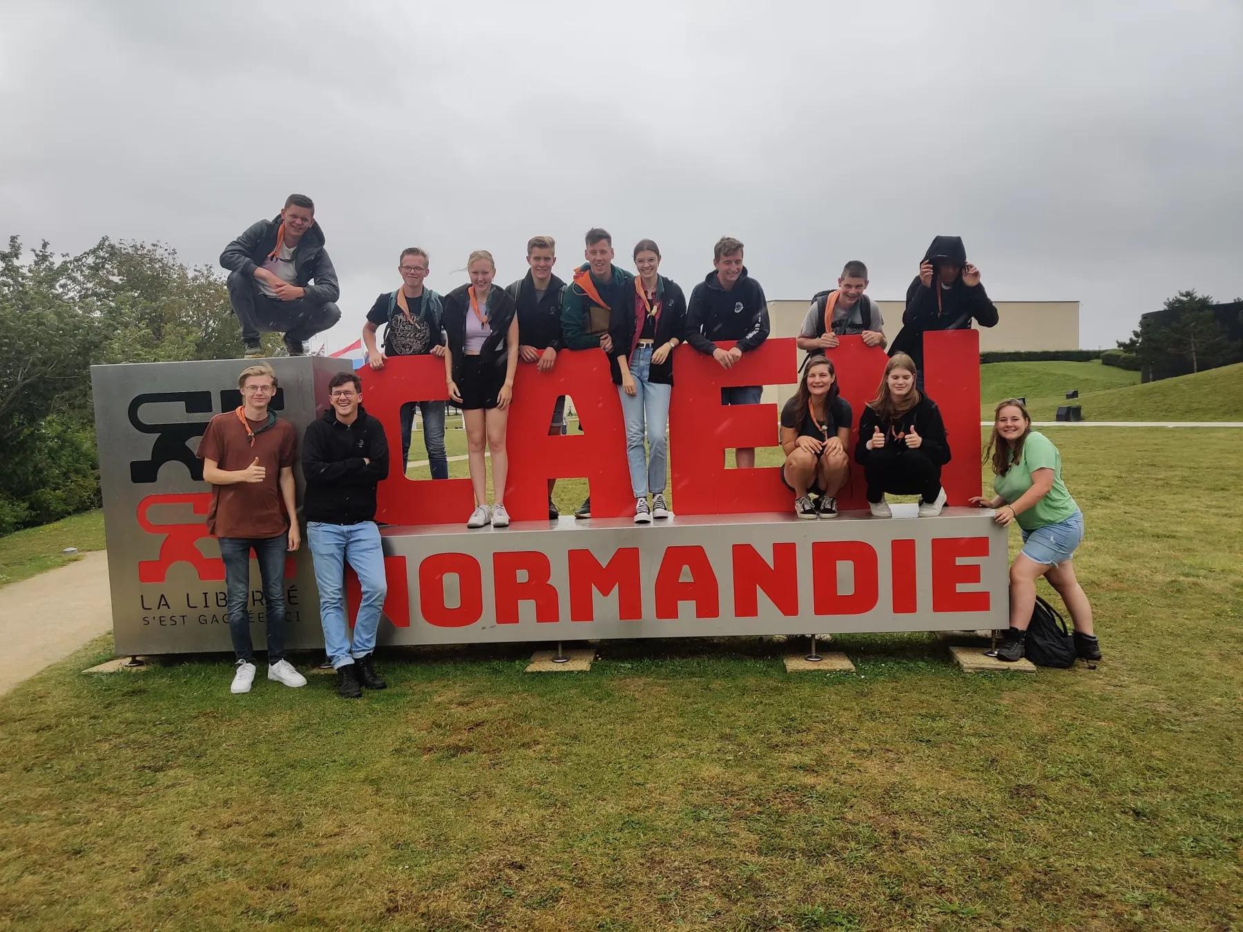 Groep scouts op en rond grote rode letters CAEN Normandie