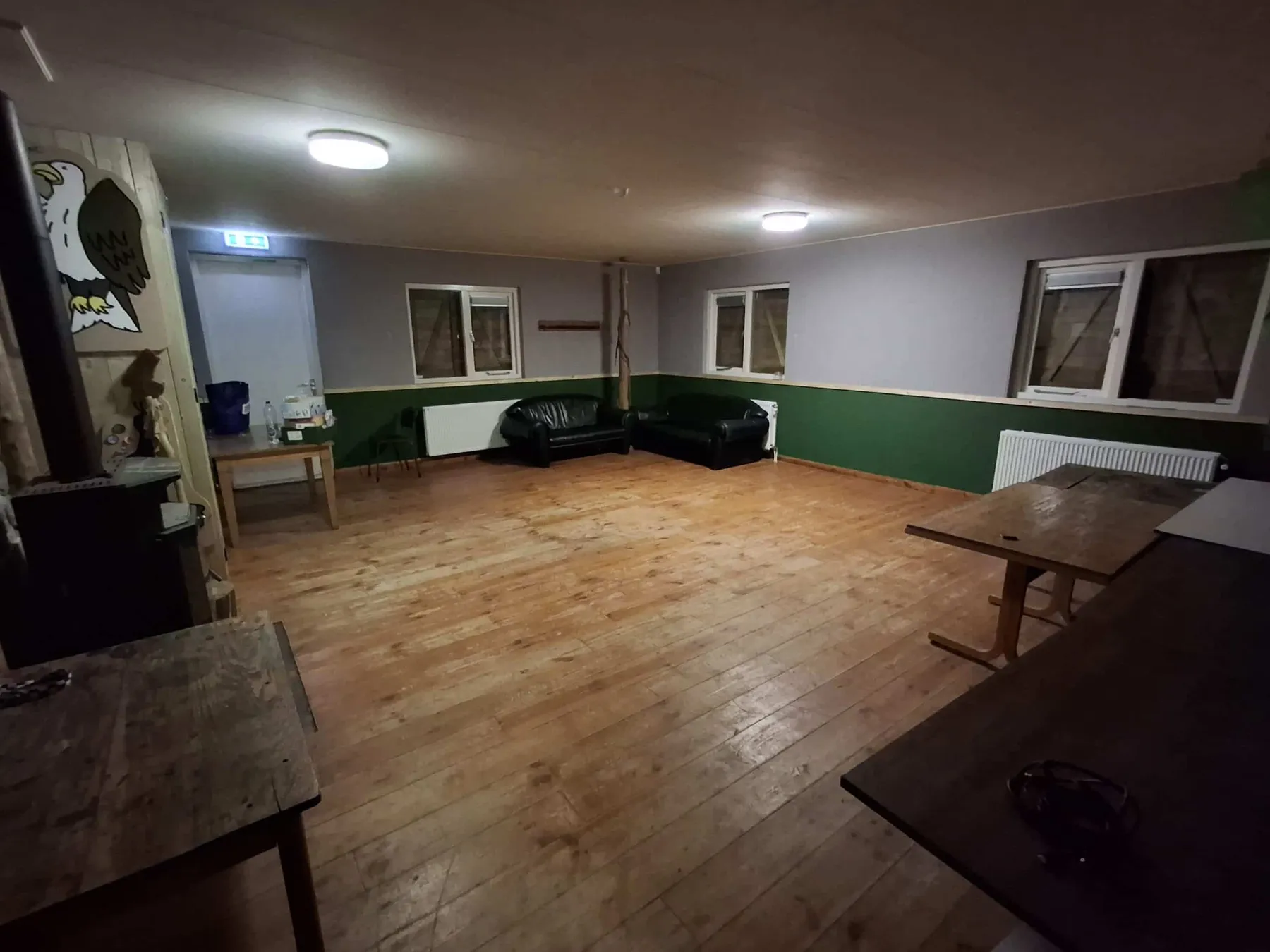 Groot verblijf met houten vloer, leren banken en lange tafels