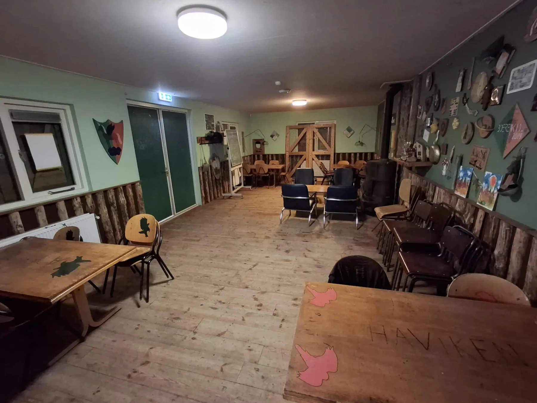 Groen verblijf met groepstafels en een zithoek met leren stoelen